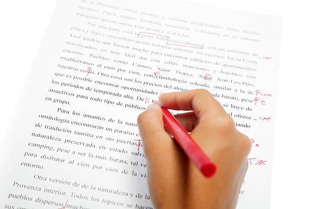 Рука делает пометки и исправляет текст в печатном документе красной ручкой.